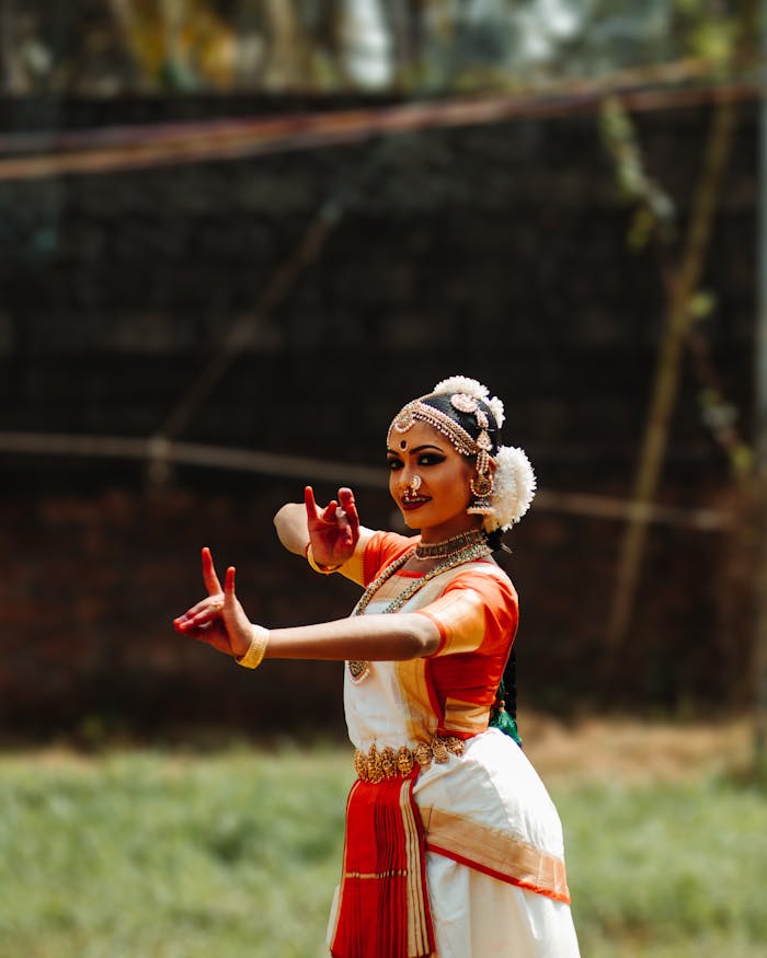 Portrait of a traditional Indian woman performing a cultural dance in vibrant attire outdoors.