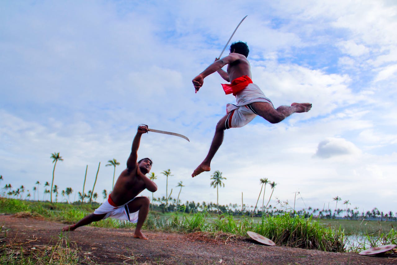 Two men perform Kalaripayattu, an Indian martial art, outdoors in Kottayam.