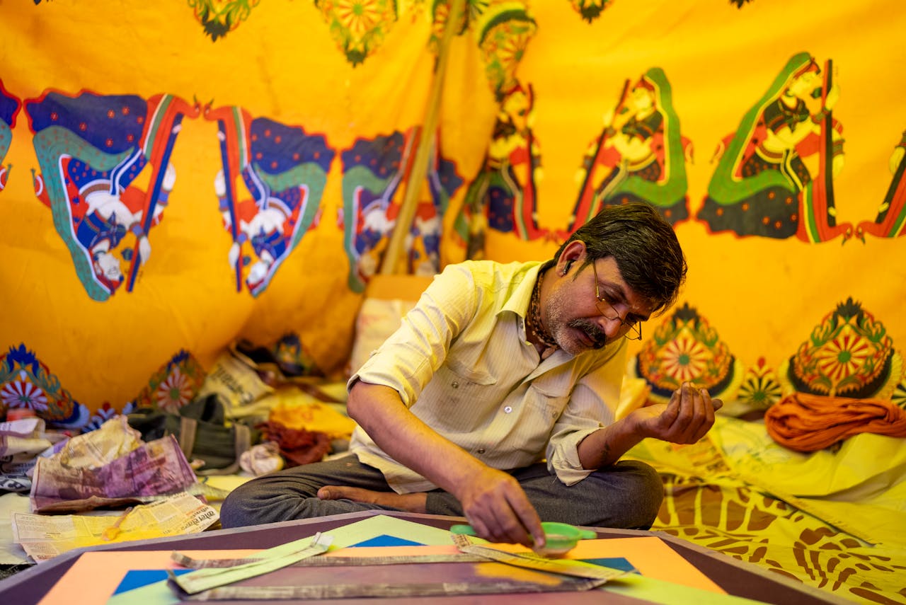 Indian artist focuses on creating traditional art using colorful yellow powder in a cultural setting.