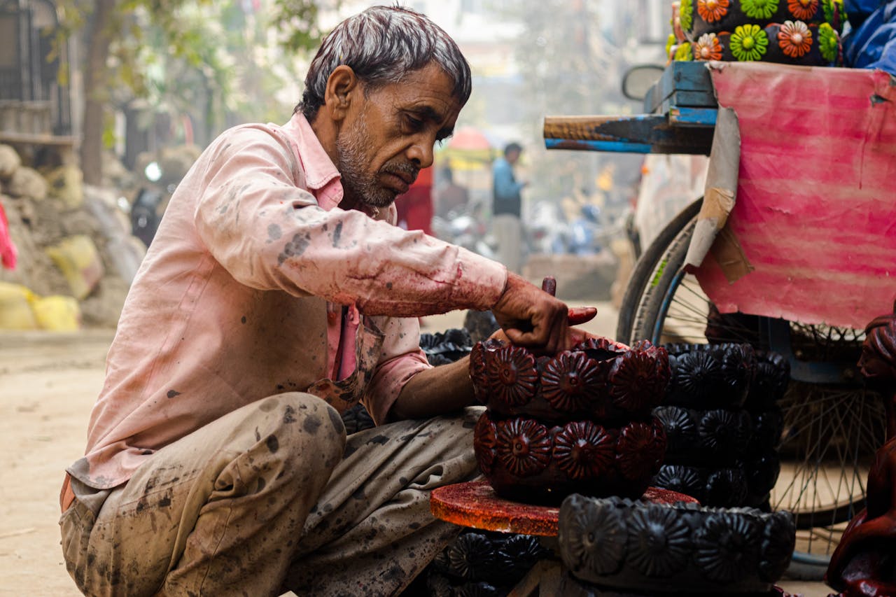 South Asian potter in a bustling street market carefully crafting traditional terracotta pottery.