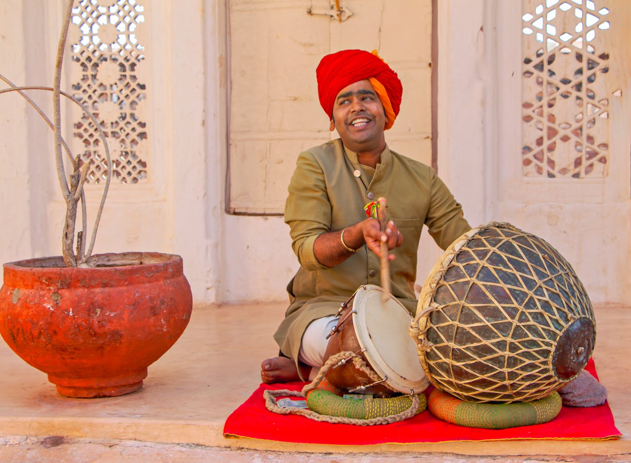 South Asian man performing traditional music with drum in Udaipur, India.