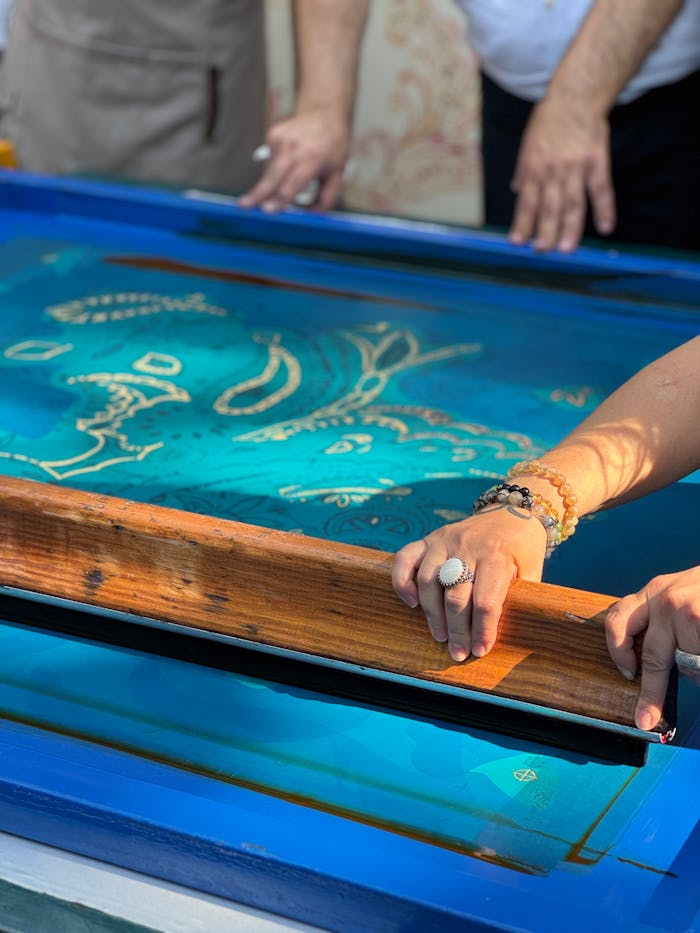 Close-up of artists engaged in traditional screen printing technique, creating unique designs.